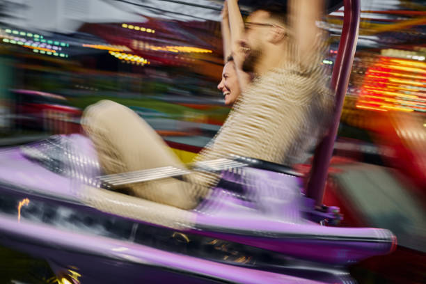 Cheerful couple having fun during amusement park ride in blurred motion.