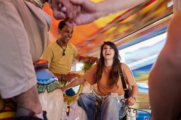 Cheerful couple enjoying on merry-go-round carousel ride in blurred motion.