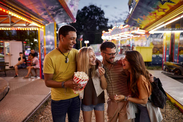 istock Happy couples talking while eating popcorn at amusement park. 1425112447
