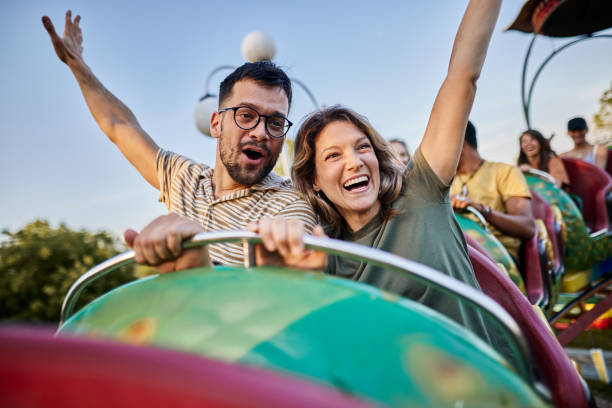 Young carefree couple having fun on rollercoaster ride at amusement park. stock photo