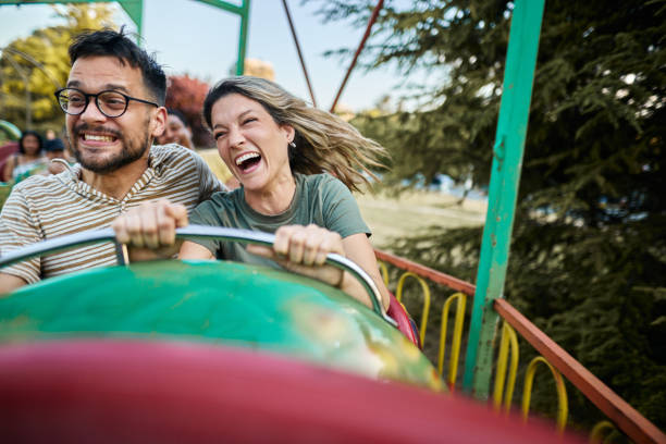 istock Cheerful couple riding on rollercoaster at amusement park. 1425113616