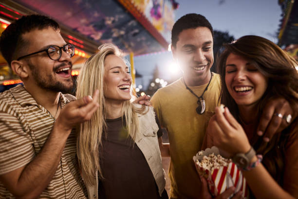 istock Happy couples talking while eating popcorn at amusement park. 1425113908