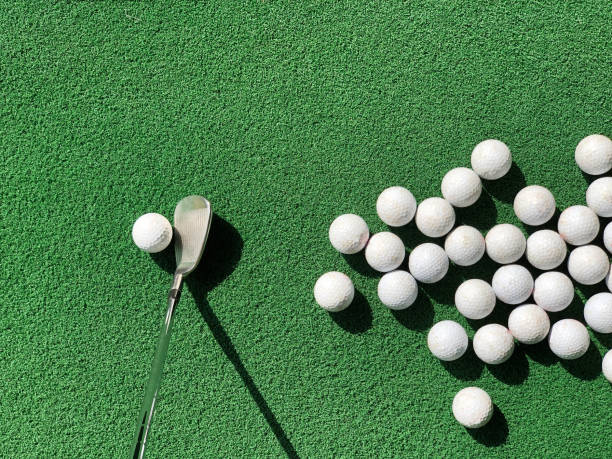 istock Group of partial appear golf balls on practice artificial grass mat with an iron address at one ball under morning sunlight. 1425118832