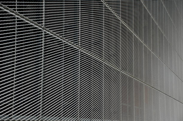 steel cladding of a building with a expanded metal lattice structure. galvanized gray nets protect the industrial building. Blue sky in contrast to a silver background, wall