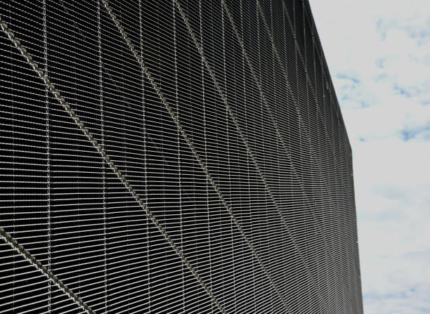 istock steel cladding of a building with a expanded metal lattice structure. galvanized gray nets protect the industrial building. Blue sky in contrast to a silver background, wall 1425119678