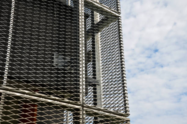 istock steel cladding of a building with a expanded metal lattice structure. galvanized gray nets protect the industrial building. Blue sky in contrast to a silver background, wall 1425119846