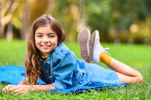 Happy relaxed kid girl smiling on a spring flowers meadow with green grass