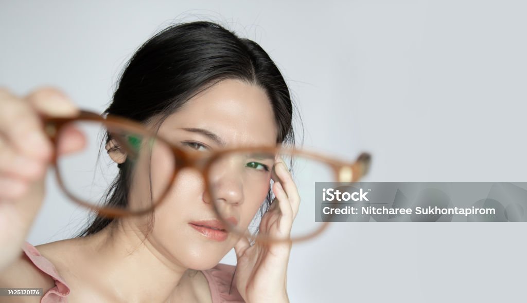 Asian beautiful woman is looking to her glasses with problem of her eye. A Asian beautiful woman is looking to her glasses with problem of her eye. Ophthalmologist Stock Photo