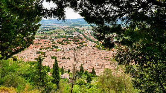 A beautiful and detailed townscape of the medieval town of Gubbio, in Umbria, seen from the woods of Monte Ingino (Mount Ingino, 880 meters above sea level). In the center, the Chiesa di San Pietro (Abbey and Church of St Peter), built by the Benedictines in the early Middle Ages and considered the second church of Gubbio after the Cathedral. An important town ally of Ancient Rome and built on the communication routes between the Tyrrhenian coast and the Adriatic coast of Italy, Gubbio is famous for its artistic treasures and considered one of the most beautiful medieval villages in Italy. This Umbrian town is also known for the life of St. Francis of Assisi and the miracle of the encounter between him and a wolf, and for the spectacular Festa dei Ceri. The Umbria region, considered the green lung of Italy for its wooded mountains, is characterized by a perfect integration between nature and the presence of man, in a context of environmental sustainability and healthy life. In addition to its immense artistic and historical heritage, Umbria is famous for its food and wine production and for the quality of the olive oil produced in these lands. Wide angle image in 16:9 and high definition format.
