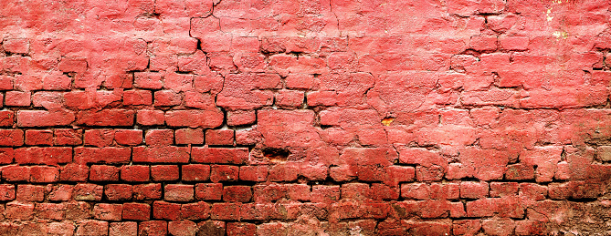 Texture of an old weathered damaged brick wall as background, ruined house facade pattern