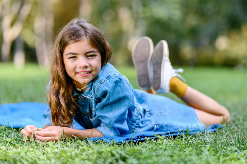 pretty blonde young girl posing with blue dungarees outside in nature and is happy