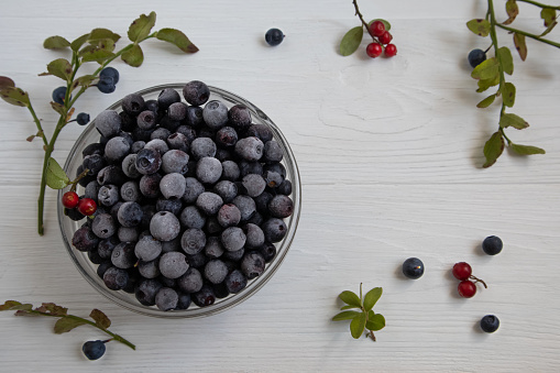 Frozen blueberries in a glass bowl, highlighted on a white background