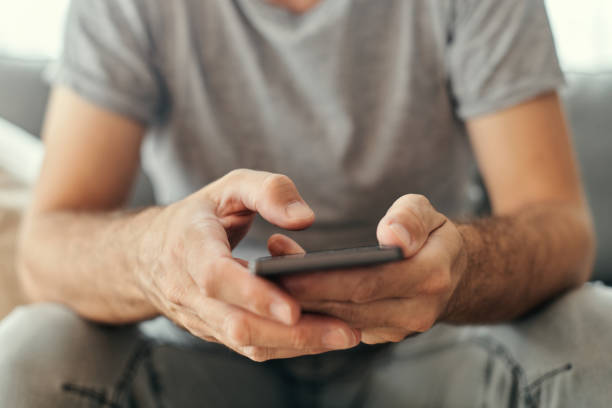 Man using mobile phone at living room sofa