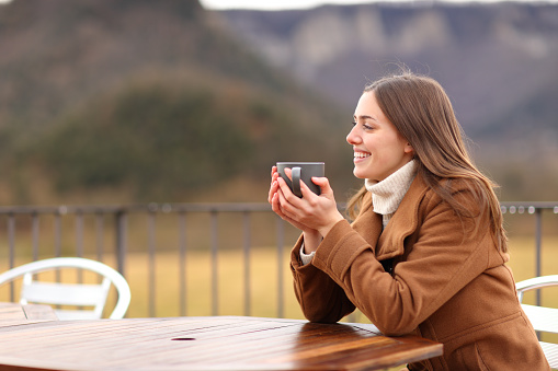 Happy woman in winter drinking in a terrace