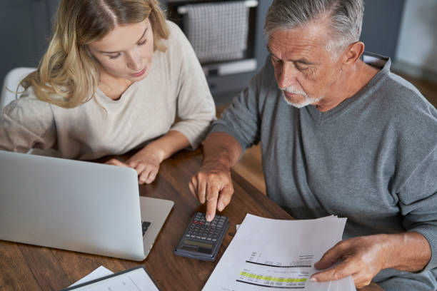 Senior man with adult daughter counting home finance stock photo