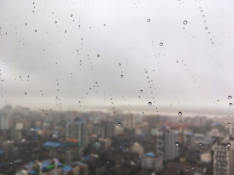 abstract random line pattern of various size of rain drop on clear  glass of Yangon city high building with blurry city vew in the background