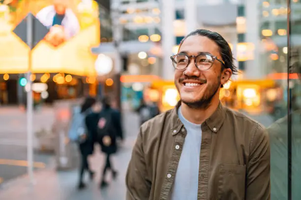 Portrait of a happy man wearing glasses outdoor in a city.