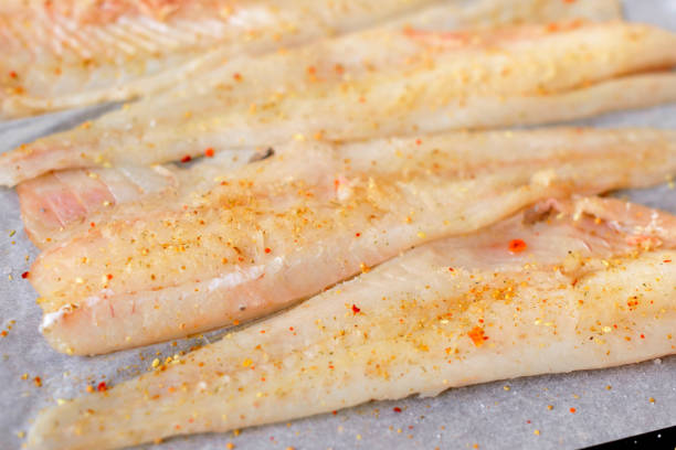 Delicious fresh fish hake fillet with spices and herbs prepared for baking in the oven. Healthy healthy food