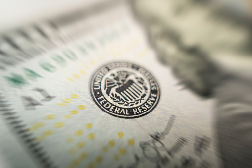 Selective focus on US Federal Reserve emblem on hundred dollars banknote as FED consider interest rate hike, economics and inflation control national organization.