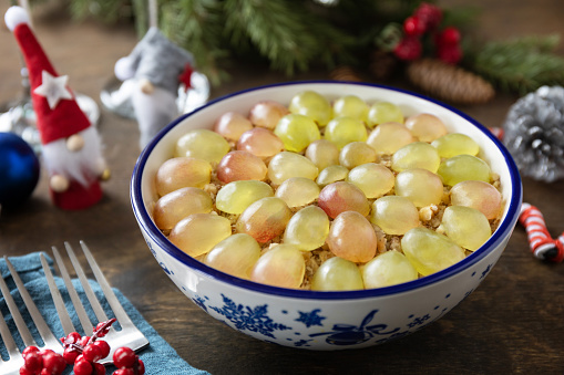 Winter Christmas salad. Delicious salad with chicken, cheese, walnuts and grapes on a festive table.