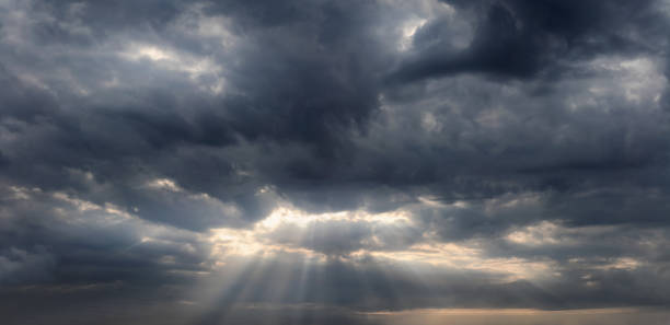 istock Sky background with sun rays shining through the dark rainy clouds. 1425138202