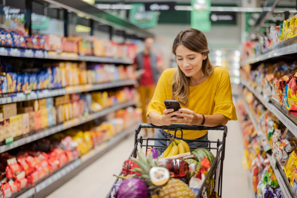 comprar productos con teléfono inteligente en la tienda de comestibles - supermercado fotografías e imágenes de stock