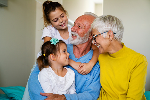 Cheerful women and kid of three different female generations meeting on home couch, hugging with love, affection, talking, chatting, laughing, enjoying family leisure, relations, bonding, having fun