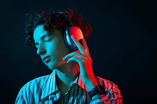 Close up studio portrait of 15 year old teen boy with headphones listening to music