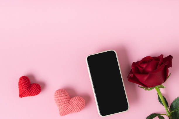istock A smartphone with a blank screen, a red rose and two knitted hearts on a pink background. 1425143464