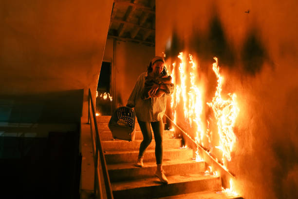 brave pompier descend les escaliers d’un immeuble de brûler et cales sauvés la jeune fille dans ses bras. feu ouvert et un pompier en arrière-plan. - civil war photos et images de collection