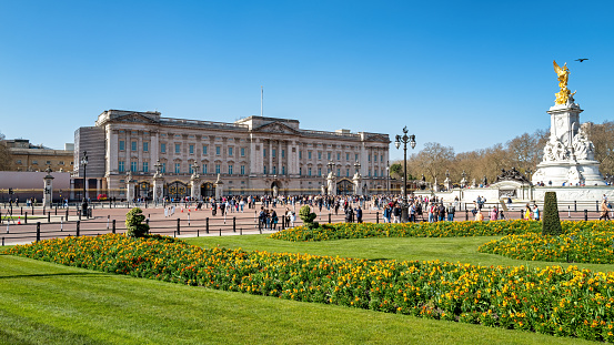 London, UK - 26 March 2022: Front facade of Buckingham Palace, with the Victoria Memorial and the Memorial Gardens. London residence of the late Queen Elizabeth II and now home to King Charles III