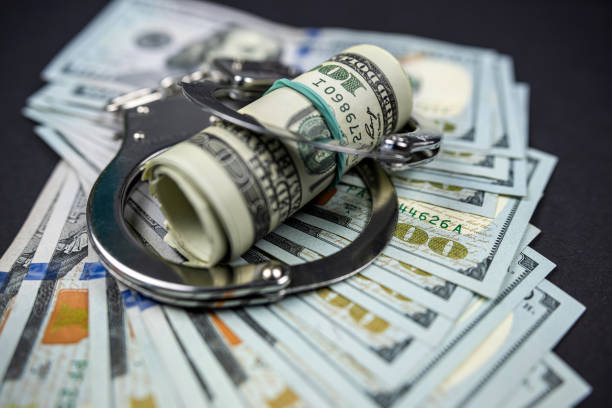 istock Handcuffs rest on hundred dollar American bills. 1425147441
