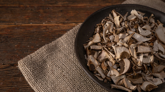 Food photography background - Dry dried forest mushrooms / Boletus edulis (king bolete) / penny bun / cep / porcini / mushroom in metal bowl on table