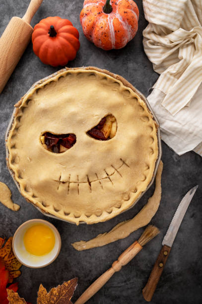 istock Cooking halloween apple pie, pumpkin face cutted in raw dough. Autumn baking concept, top view. 1425151037