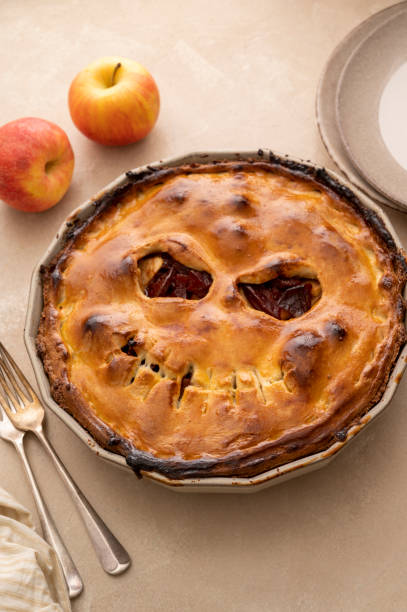 istock Halloween pie with funny pumpkin face carved on pie, top view. Autumn baking 1425151131