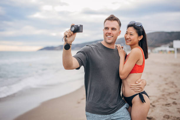 istock Young multi ethnic couple taking pictures with camera on a beach 1425151157