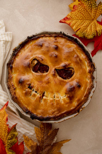 istock Halloween pie with funny pumpkin face carved on pie, top view. Autumn baking 1425151812