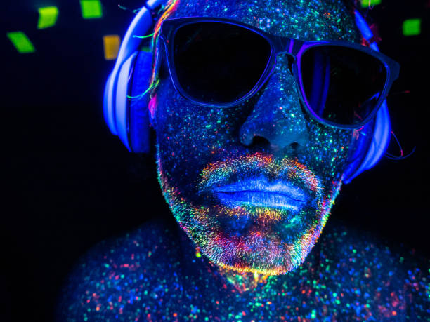 un dj con auriculares bajo luces uv - face paint audio fotografías e imágenes de stock