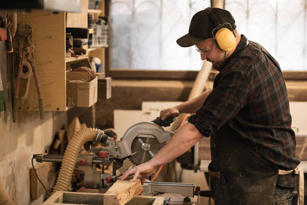 istock Carpenter worker in protective apron and headphones use modern grinder machine to process cut wood with saw in workshop 1425153023