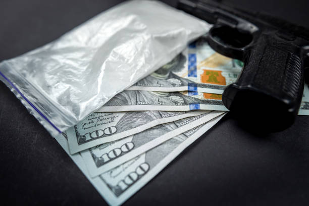 de la cocaïne dans des sacs à côté de dollars et un pistolet isolé sur fond noir. - narcotic gun medicine currency photos et images de collection