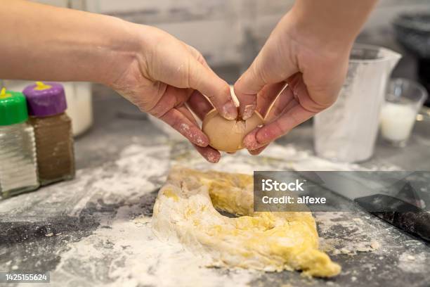 Woman Is Fighting In The Kitchen Breaking Eggs Into Flour And Kneading Dough Into Dumplings Stock Photo - Download Image Now