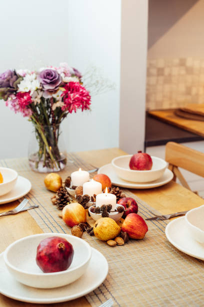 istock Fall table setting for celebration Thanksgiving day family party. Autumn composition with candles, fruits, nuts and cones. Plates with pumpkins and pomegranate. Natural autumn decor. Selective focus 1425155804