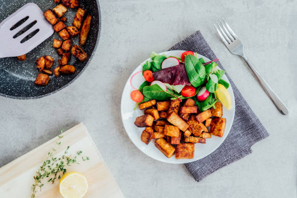 Top view healthy salad with cherry tomato, beetroot straws, spinash and lettuce leaves and portion of roasted tempeh, made of fermented soy bean on plate. Plant based protein. Healthy eating. Go vegan