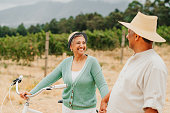Retirement, bike and senior couple in the vineyard, countryside or farm together enjoying bonding time. Nature, cycling and happy elderly man and woman in love walking in winery field