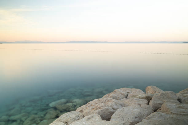 Pebble beach at beautiful sunset with waves and twilight sky, scenic coastal seascape for summer travel