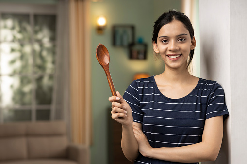 Beautiful anger girl holding mixed spoon. Looking at camera.
