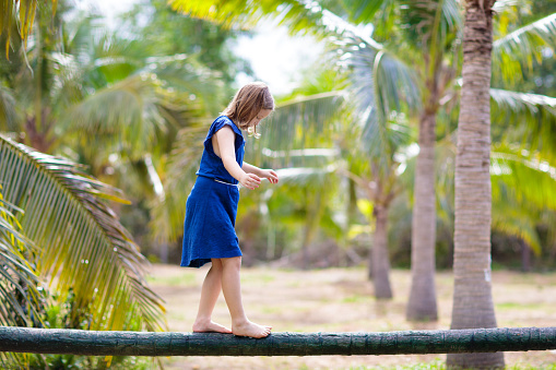 Kids on beam. Children on playground in tropical resort with coconut palm trees. Summer beach fun. Family vacation in Asia. Little girl playing outdoor.