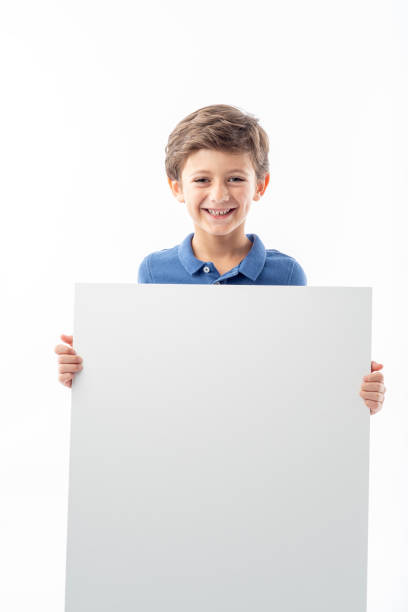 istock Funny child showing a white advertising poster with space for text. 1425162243