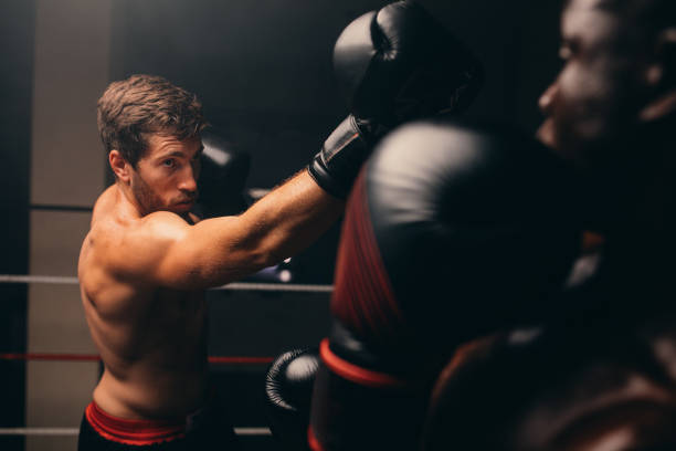 atleta muscoloso che colpisce il suo avversario durante un combattimento di boxe - undercutting foto e immagini stock