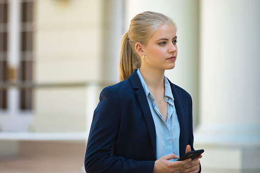 Side view of a young business woman on the phone in the city